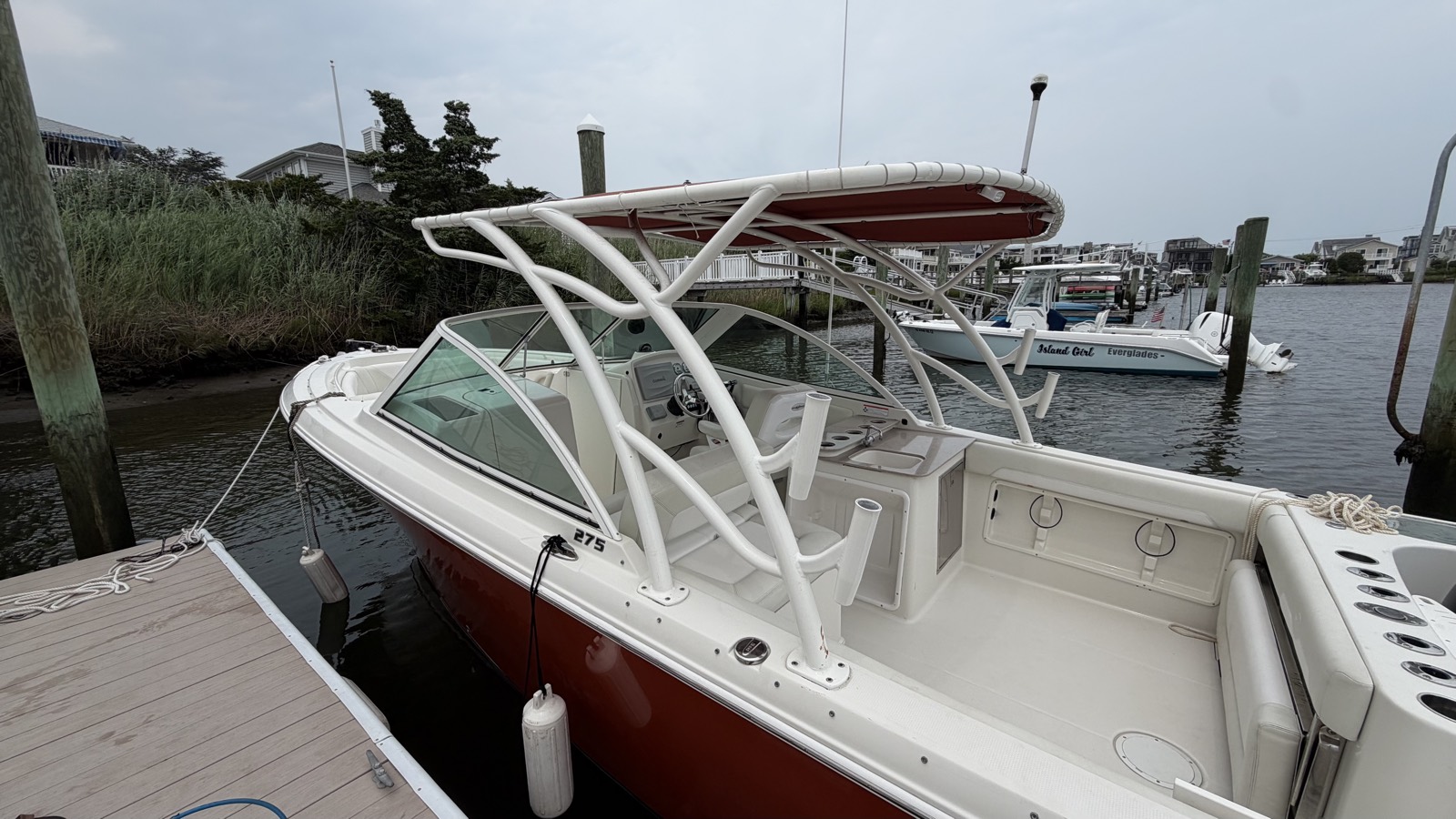 A Sailfish 275 alongside the dock, red hull polished and the hardtop canvas clean.